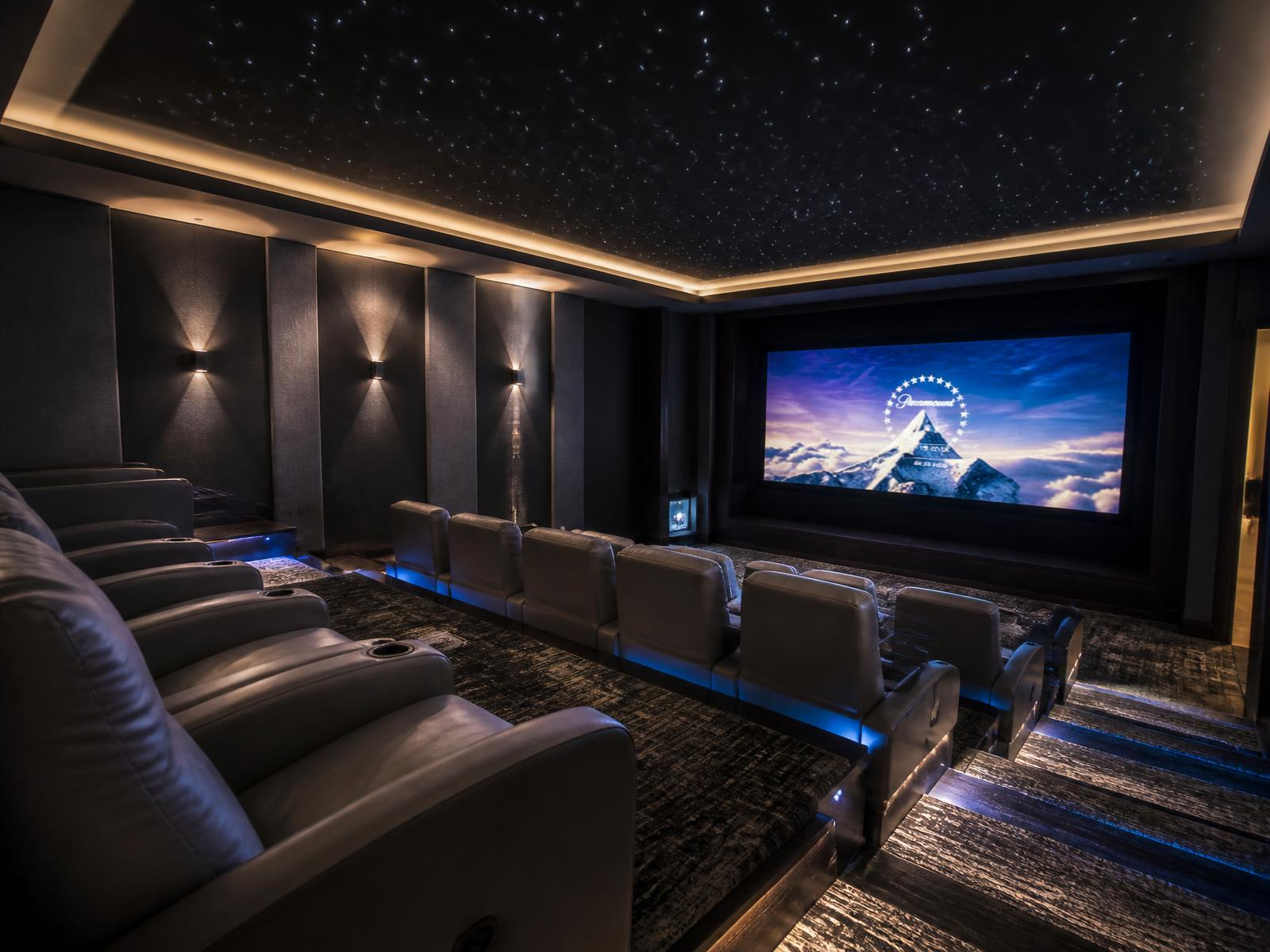 A private theater with tiered recliner seating and a large screen.