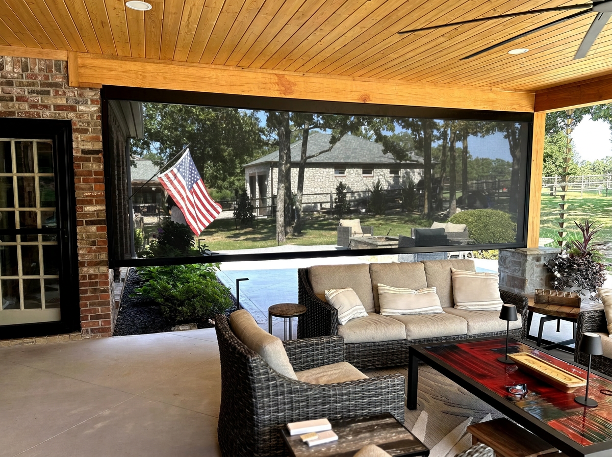 A covered stone patio with a motorized retractable screen lowered along the opening.